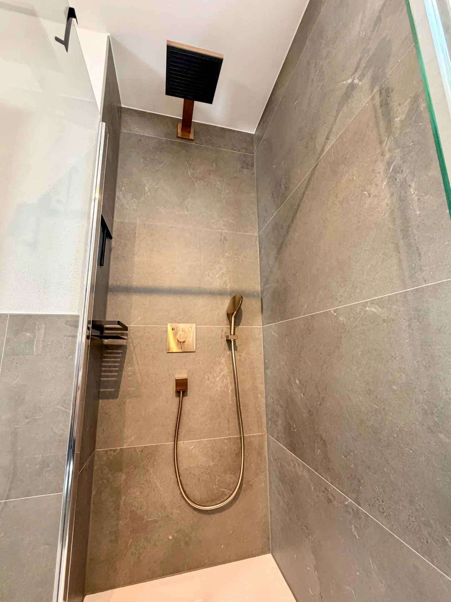 Bodengleiche Dusche im Badezimmer des Markt Quartiers in Nierstein mit großem Regenduschkopf und grauen Fliesen.
