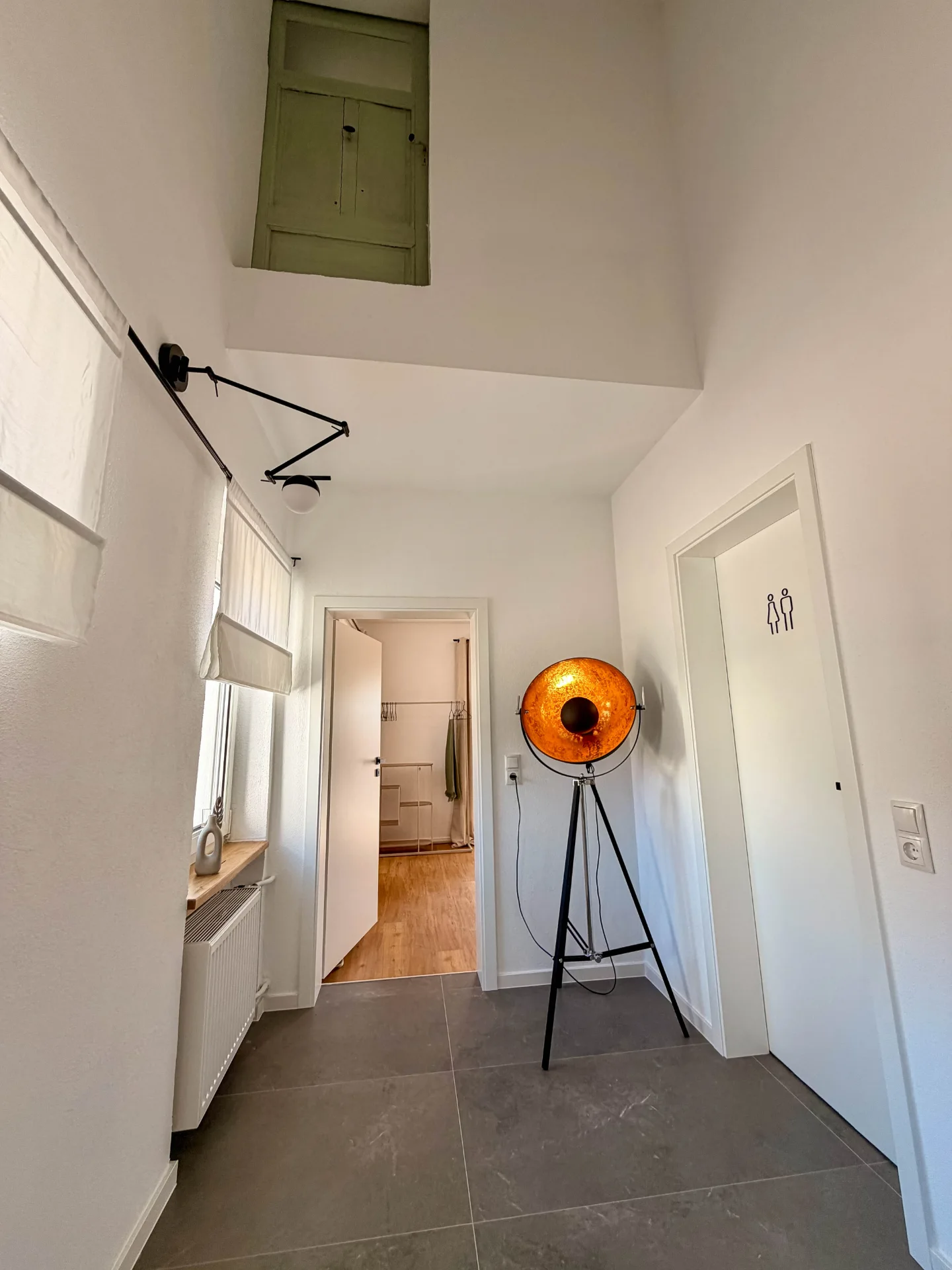Heller Flur des Markt Quartiers in Nierstein mit großer Designleuchte, Fenstern und Zugang zum Schlafzimmer.