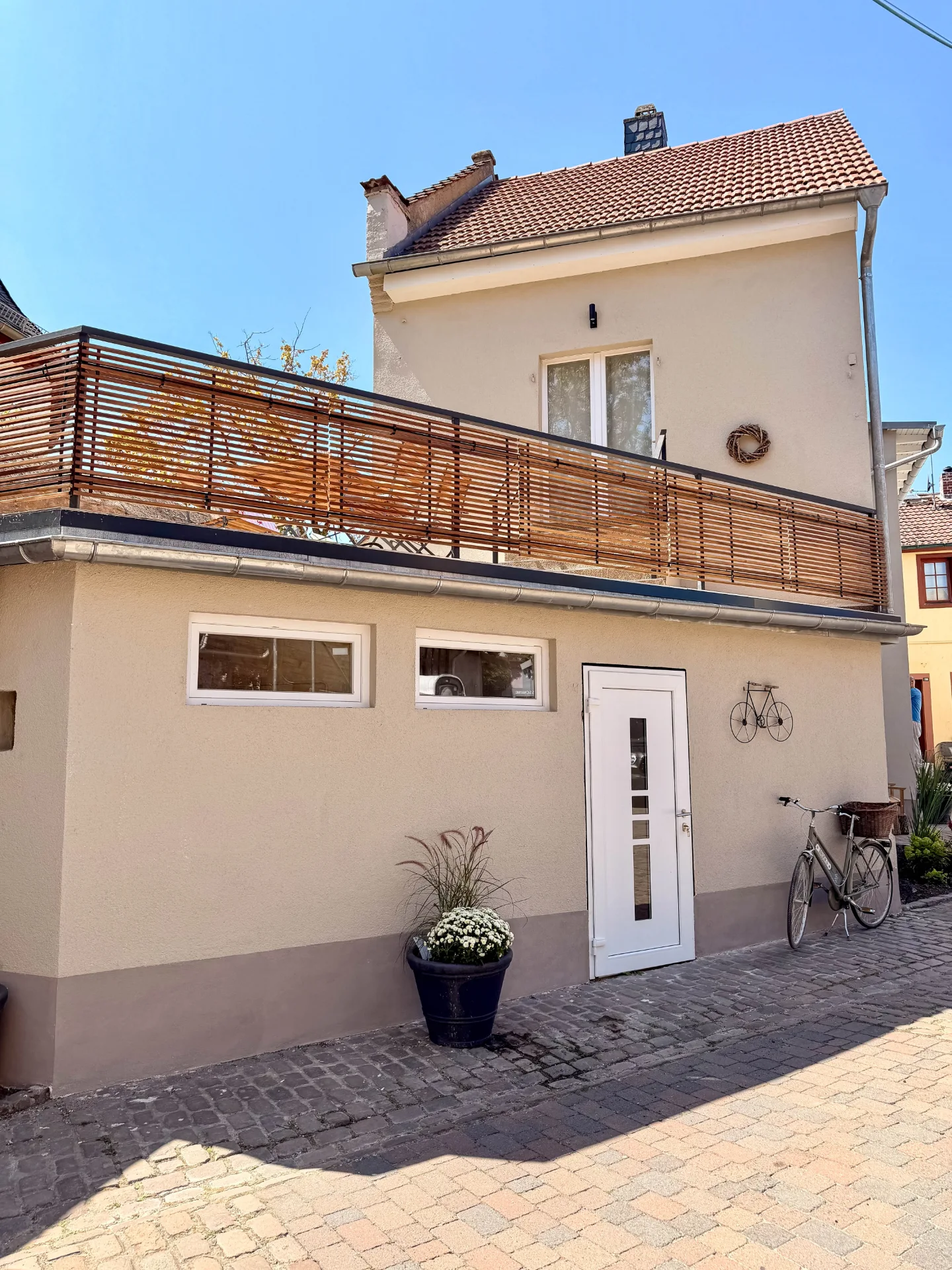Außenansicht des Markt Quartiers in Nierstein mit Fahrradgarage, Balkon und Fahrrad vor dem Gebäude.