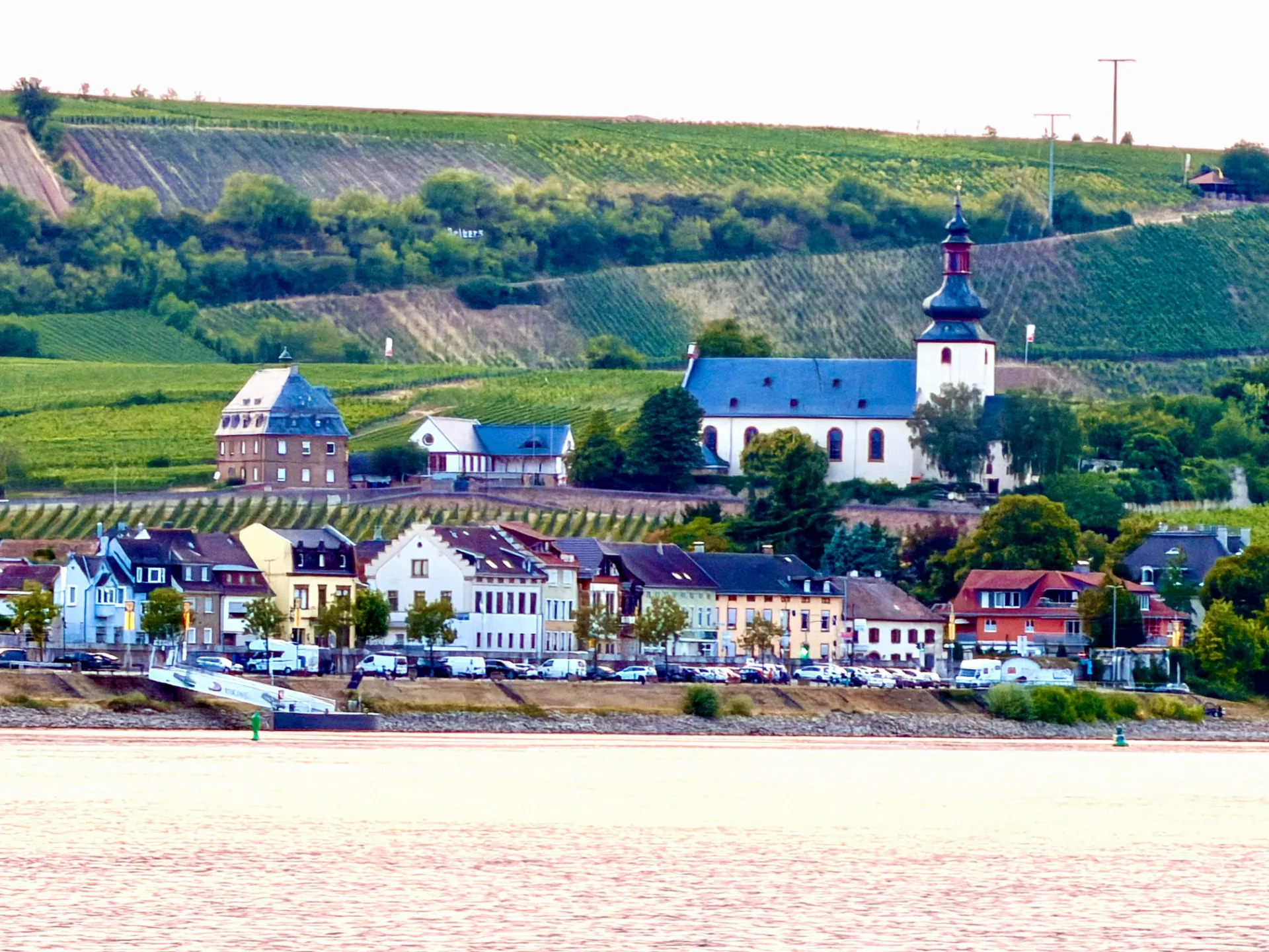 Ortsansicht von Nierstein über den Rhein mit Kirche, Häusern und den Weinbergen des Roten Hangs.