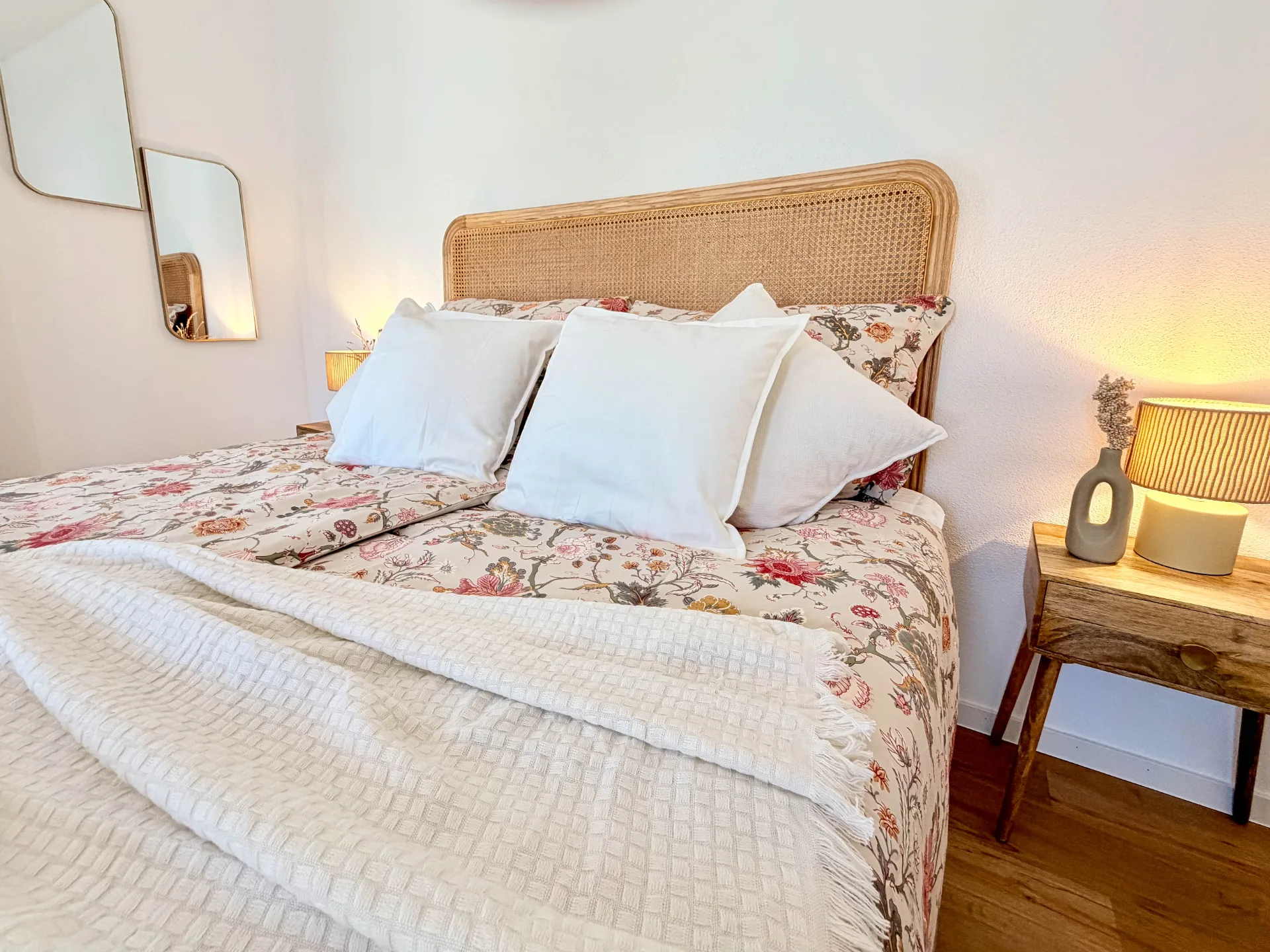 Gemütliches Doppelbett im Markt Quartier mit floral gemusterter Bettwäsche, weißen Kissen und beleuchteten Nachttischen.